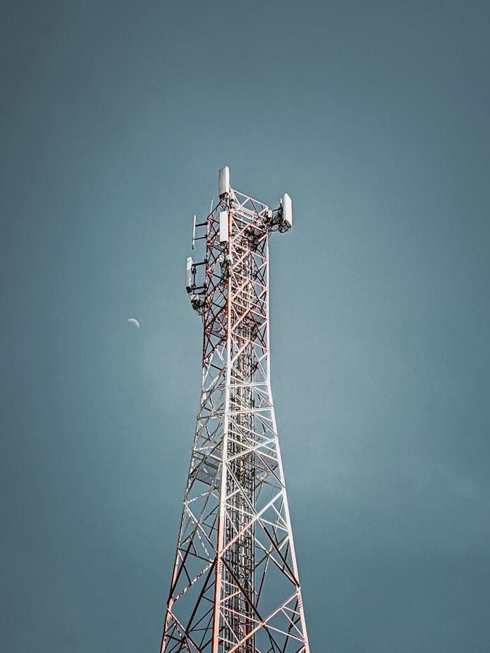 A tall telecommunication tower against a clear blue sky, symbolizing modern communication infrastructure.