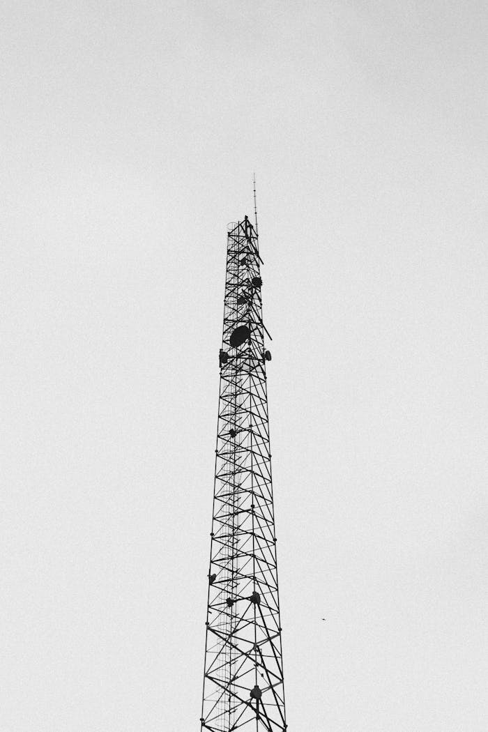 Black and white photo of a tall communication tower against a clear sky.